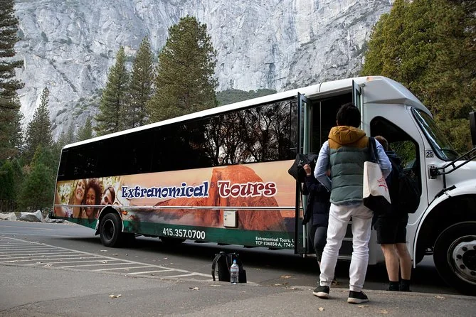 Viaggiatori che salgono su un minibus turistico nella Yosemite Valley sotto una parete di granito