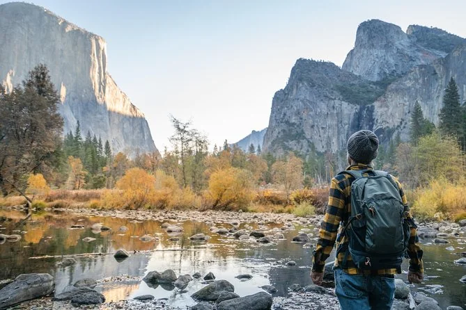 Ein Wanderer mit Rucksack am Merced River im Herbst, dahinter El Capitan